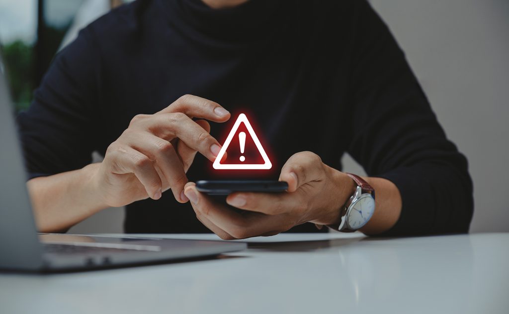 Image d'un homme sur son téléphone qui reçoit une fausse amende.